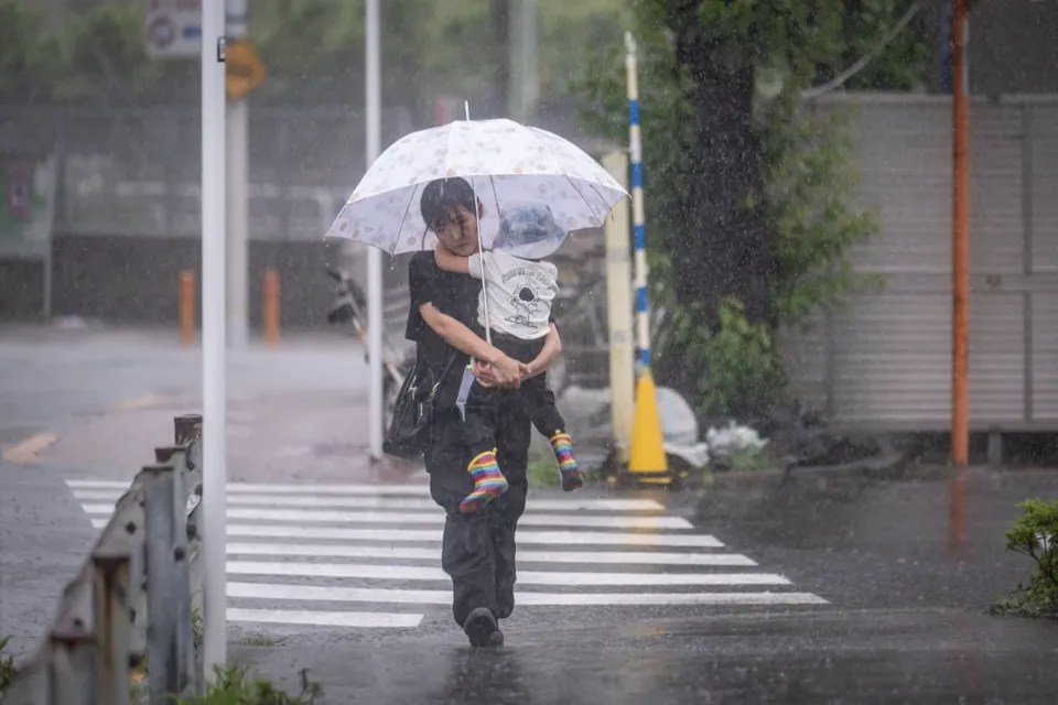 woman holding her child walks through heavy rain brought by severe tropical storm Jangmi in Tokyo on June 3, 2026.
