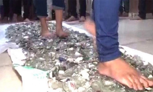 Indian students walk barefoot on broken glass Indian students walk barefoot on broken glass