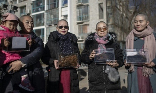 Wife of detained China activist goes bald 